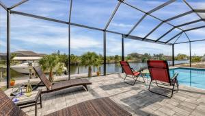 a patio with a pool and two chairs and a table at Luxury Contemporary Style House on Charlotte Harbor Area Charlotte County House 5841 in Placida