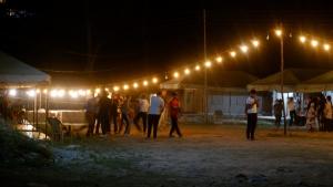 a group of people standing under a tent at night at Soma Caves Tents in Jagatsukh