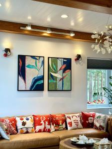 ein Wohnzimmer mit einem Sofa und vier Gemälden an der Wand in der Unterkunft Violet Villa Đà Lạt in Xuan An