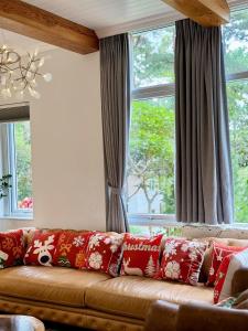 eine braune Couch mit roten Kissen vor dem Fenster in der Unterkunft Violet Villa Đà Lạt in Xuan An