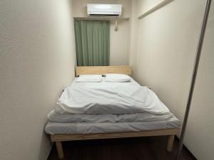 - un petit lit dans une chambre avec un miroir dans l'établissement Riverside Omori, à Tokyo
