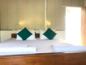 a bed with green and white pillows on it at Salt Bay Kite and Dive Resort in Kalpitiya