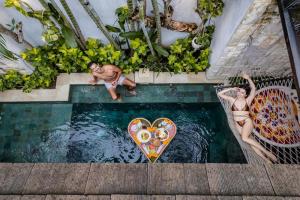 スミニャックにあるAksari Villa Seminyak by Ini Vie Hospitalityのサーフボード付きプールの男女