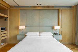 a bedroom with a large white bed with two lamps at Bangkok Marriott Hotel Sukhumvit in Bangkok