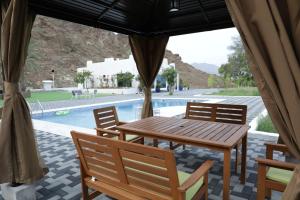 a wooden table and chairs next to a swimming pool at Moon mountain resort in Sharm