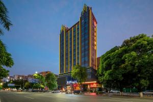 wysoki budynek na ulicy miejskiej w nocy w obiekcie Calvin International Hotel Guangzhou Baiyun International Airport Huadu Plaza Branch - Free Deliver Service to Guangzhou Baiyun International Airport & Free Deliver Service to Canton Fair Complex During Canton Fair Period w mieście Huadu