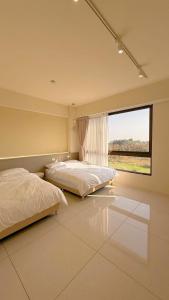 two beds in a bedroom with a large window at 鹿港 尋鹿好旅 民宿 in Lugang