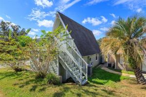 a house with a staircase leading up to a house with palm trees at Orlando Home 6430: Purpose-Driven A-Frame Vacation Home in Clermont