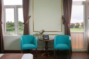 two chairs and a table in a room with windows at Royal Hotel Bắc Ninh in Bắc Ninh