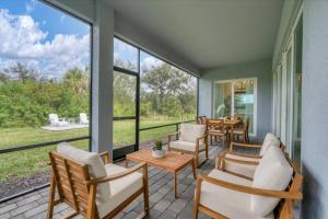 eine Veranda mit Stühlen und Tischen und großen Fenstern in der Unterkunft Charlotte County 5886: Perfect Gulf Coast Retreat in Port Charlotte