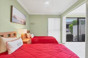 a bedroom with two beds with red sheets and a balcony at Beachside Bliss: Sarasota County Condo 1006 Awaits in Venice +26 photos