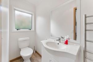 a white bathroom with a toilet and a sink at Hilltop Hideaway in Taupo +11 photos