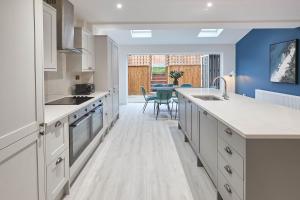 una cocina con armarios blancos y una pared azul en Host & Stay - Iburn House, en Sleights 16 fotos más