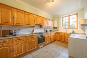 a kitchen with wooden cabinets and a stove top oven at The Coach House in Abergavenny +21 photos