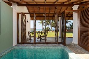 un patio abierto con piscina, mesa y sillas en Oruva Beachside Villa, en Galle