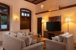 Una sala de estar con sillas y un televisor de pantalla plana. en Oruva Beachside Villa, en Galle