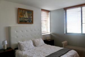 a bedroom with a white bed and two windows at 101Infinity in Bloubergstrand +12 photos