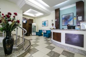 a lobby with a counter with a vase of flowers at Grand Prix Hotel in Cascavel