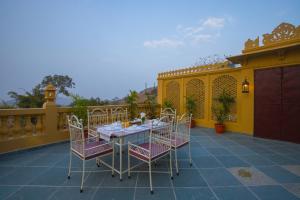 a patio with a table and chairs and a yellow fence at ELIVAAS Amber Royale 3 BHK with Pvt Pool & Terrace in Udaipur