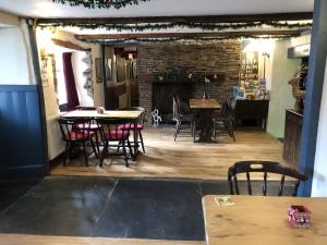 Un comedor con mesas y sillas y una chimenea. en Blue Lion Inn, en Lewdown