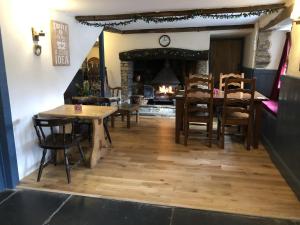 Un comedor con mesas y sillas y una chimenea. en Blue Lion Inn, en Lewdown