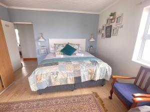a bedroom with a large bed and a chair at Calypso beach holiday in Langebaan