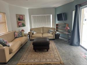 a living room with two couches and a ottoman at Calypso beach holiday in Langebaan