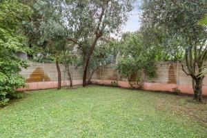 a yard with trees in front of a wall at Maison Jacoulet - Welkeys in Saint-Cloud