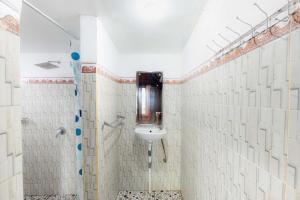 ein weiß gefliestes Badezimmer mit Waschbecken und Dusche in der Unterkunft Coconut Hill Cottage in Nusa Penida + 49 Fotos