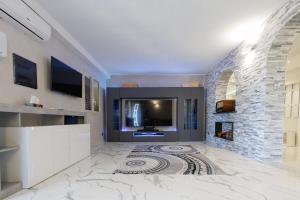 a living room with a tv and a stone fireplace at Villa Caruso in Avola