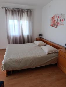 a bedroom with a bed and a window with curtains at Apartmani Danica in Pirovac