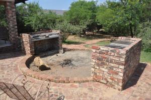 een stenen vuurplaats in het midden van een tuin bij Thorntree Lodge in Potchefstroom