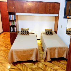 two beds in a room with a book shelf at Bohemia Baires Balvanera in Buenos Aires