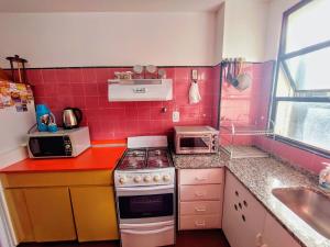 a pink kitchen with a stove and a sink at Bohemia Baires Balvanera in Buenos Aires