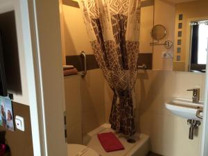 a bathroom with a toilet and a shower curtain at Hotel Sandmanns am Dom in Cologne
