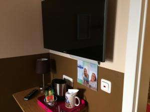 a flat screen tv hanging on a wall with a table at Hotel Sandmanns am Dom in Cologne