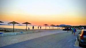 a beach with umbrellas and people walking on the beach at Apartmani Danica in Pirovac +8 photos