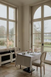 a dining room with a table and chairs and windows at B&B Kasteel Den Tip in Arendonk