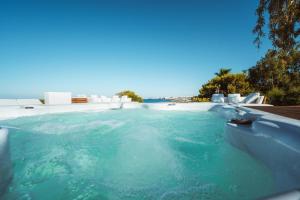 a swimming pool with blue water and white chairs at MareLuxe & Pool in Polignano a Mare