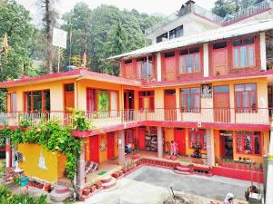 un grande edificio colorato con cortile di fronte di Om Yoga Ashram - 7 Days Yoga Meditation Retreat a Dharamshala