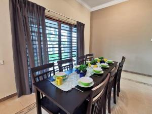 a dining room table with chairs and a black table with dishes at Kuantan Air Putih 4 rooms 3 bathrooms Town area in Kuantan