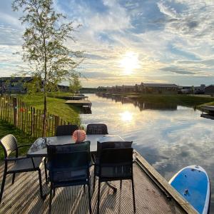 a table and chairs sitting on a deck next to a river at Elegantes Chalet am Wasser mit Steg Klimaanlage Ferienhaus am See Niederlande in Kampen