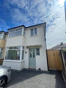 a white house with a car parked in front of it at The Crescent-Modern Coastal Home in Blackpool