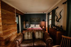 a bedroom with a bed and a leather couch at The Cabins Hogsback in Hogsback +12 photos