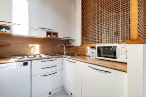a white kitchen with a microwave and a sink at Cozy 2-Bedroom Stay at Lido di Venezia in Lido