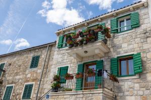 een stenen gebouw met groene luiken en bloembakken bij Center Brela Apartment in Brela