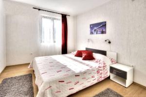 a bedroom with a bed with a red pillow and a window at Apartments Grozdana in Baška