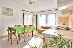 a kitchen and dining room with a green table and chairs at Apartments Grozdana in Baška
