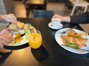 ein Tisch mit zwei Tellern Essen und einem Glas Orangensaft in der Unterkunft VESK Svečių Namai in Druskininkai