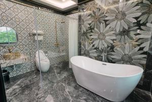 a bathroom with a tub and a flower patterned wall at Bao Ngọc Hotel Dương Nội in Hanoi